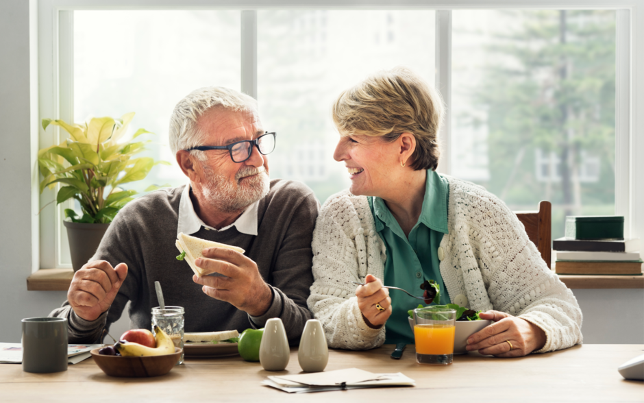 casal da terceira idade com um ar feliz à mesa comendo refeição saudável