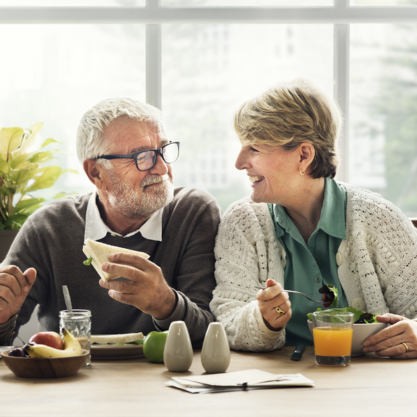 casal da terceira idade com um ar feliz à mesa comendo refeição saudável