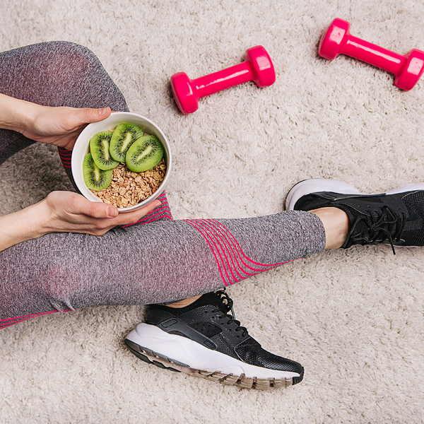 Desportista com uma taça de papas de aveia e kiwi um exemplo de refeição saudável após exercício físico